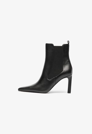 Bottine en cuir noir avec un bout pointu, des panneaux latéraux élastiques et un talon aiguille. Texture lisse avec un minimalisme dans les détails.