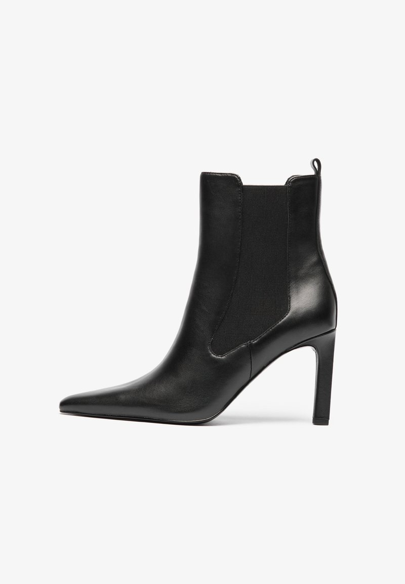 Svarte skinn ankelstøvler med spiss tå, elastiske sidepaneler og stiletthæler. Jevn tekstur med minimal detaljering.
