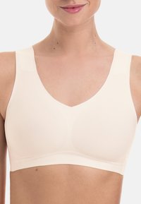 Light beige bralette with a v-neck design, wide straps, seamless finish, and smooth texture, featuring subtle contours for support.