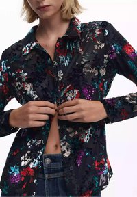 Blusa nera a fiori con chiusura a bottoni sul davanti, caratterizzata da vivaci motivi multicolori, maniche lunghe e tessuto texturizzato.