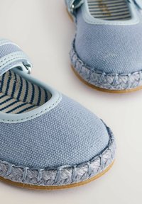 Jasnoniebieskie buty z tkaniny o fakturowanym wykończeniu, regulowany pasek oraz pleciona, jasnoniebiesko-szara podeszwa. Widoczna wyściółka w paski.