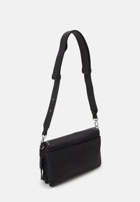 Sort rektangulær crossbodytaske med justerbar bred rem, sølvfarvede metaldele og duskdetalje på siden, vist på en hvid baggrund.