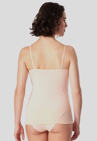 Light pink camisole with thin straps, smooth texture, and a relaxed fit, paired with matching underwear, displayed from the back.