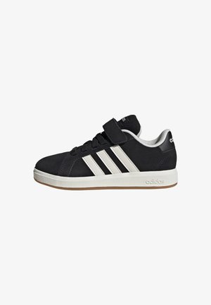 Sneaker Adidas nera con strisce bianche, chiusura in velcro e suola bianca, mostrata di lato su sfondo bianco.