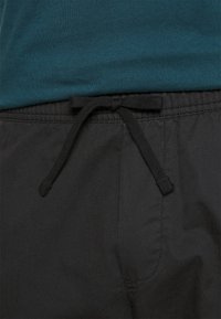 Zwarte shorts met een elastische tailleband en een striksluiting, met een gladde textuur en minimale stikdetails.