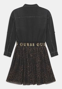 Czarna denimowa bluzka z kołnierzykiem i długimi rękawami, połączona z spódnicą z szyfonu w panterkę, podkreśloną złotą gumką w talii z napisem "Guess".