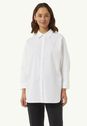 Weißes Button-Down-Hemd aus Baumwolle mit langen Ärmeln, ausgestattet mit einem klassischen Kragen und dezentem Stickdetails auf der Schulter.