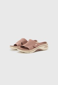 Svetloružové šľapky na slip-on s textúrovaným vrchom, otvorenou špičkou a polstrovanou podrážkou so kontrastným béžovým lemom a logom značky.