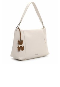 Hvid læderhåndtaske med tekstureret finish, inkluderer en brun bamseformet vedhæng som accent. Har et enkelt topgreb og sidelomme.