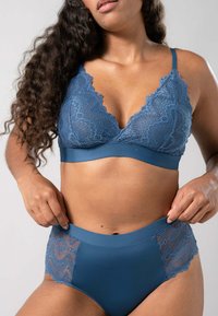Bralett med spetsdetaljer och högmidjade trosor i blått. Braletten har en scallopmönstrad spetsdesign; trosorna har spetspaneler på sidorna.