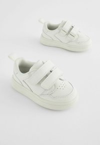 Baskets en cuir blanc avec deux bandes Velcro, bout arrondi, détails perforés à l'avant et intérieur rembourré pour un confort optimal.