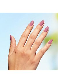 Glänzende, mandelförmige Nägel in einem dezenten Rosaton. Hand mit heller Hautfarbe vor einem sanften blauen Hintergrund positioniert.