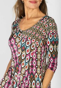 Mönstrad tunika i flera färger med geometrisk design i brun, rosa, blå och vit. Har en rundad halsringning och trekvartärmar.