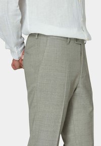 Hellgraue, maßgeschneiderte Hose aus strukturiertem Stoff mit Seitentaschen und glattem Bund, kombiniert mit einem weißen Langarmhemd.