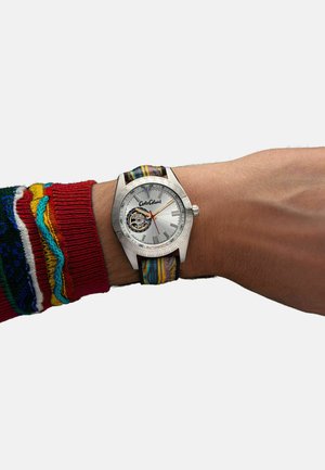 Silberne Automatik-Uhr mit einem gemusterten Armband. Verfügt über ein weißes Ziffernblatt, schwarze Akzente und einen transparenten Gehäuseboden, der das Uhrwerk zeigt.