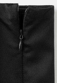 Pochette en tissu noir avec fermeture éclair, présentant une texture lisse et un design élégant. Le tirette de la fermeture est un petit onglet noir mat.