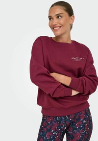 Bordeaux sweatshirt met een ronde hals, geribbelde manchetten en zoom. Gecombineerd met patroonstradeleggings in tinten bordeaux, marineblauw en wit.