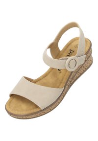 Sandalia de cuña beige con parte superior de piel suave y tiras anchas. Presenta un acento metálico circular y una suela de estilo corcho texturizada.