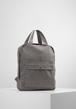 Zaino in tessuto grigio con due manici superiori, una tasca frontale con chiusura a scatto e forma rettangolare. Texture liscia con design minimale.