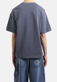 Szara bawełniana koszulka z luźnym krojem, krótkimi rękawami i okrągłym dekoltem. Posiada minimalistyczne przeszycia i gładką teksturę.