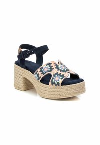 Sandal de esparto azul marino con tacón cuadrado, adornado con bordados florales en tonos rosa y verde, correa alrededor del tobillo y suela de yute trenzado.