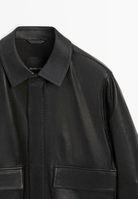 Sort læderjakke med klassisk krave, to frontlommer og glat tekstur med et elegant design. Mærke synligt inde i kraven.