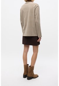 Top beige de manga larga a rayas con cuello redondo, combinado con una falda de pana marrón oscuro y botines de ante marrón.