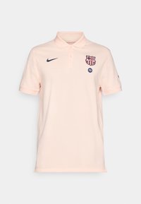 Light pink Nike polo shirt with FC Barcelona crest and Spotify logo on front, short sleeves, and buttoned collar.