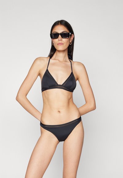 Black bikini featuring a triangular top with thin straps and a low-rise bottom, made of smooth, stretchy fabric with subtle detailing.