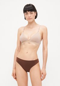 Beha en slip set in lichtbeige en donkerbruin. De beha heeft een driehoekig ontwerp met verstelbare bandjes; de slip heeft een soepele textuur.