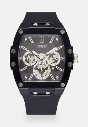 Orologio analogico nero con cassa rettangolare, cinturino in gomma, quadrante trasparente che mostra dettagli argentati e più sub-quadranti per cronografo.