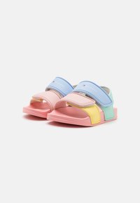 Farverige sandaler med en pink bund, blå, grønne og gule remme, med et fladt design og velcrolukninger for nem tilpasning.