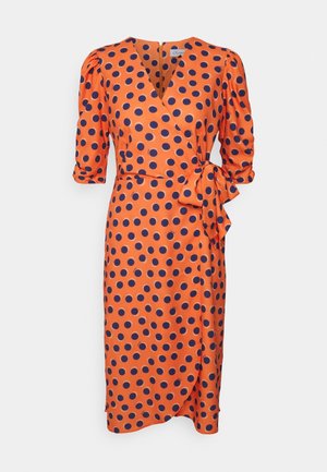 Vestido cruzado naranja con lunares azul marino, mangas cortas abullonadas, escote en V y lazada lateral, largo hasta la rodilla.