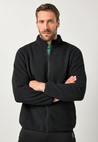 Chaqueta de forro polar negra con cuello alto y cremallera frontal. Textura suave, mangas largas y detalle sutil de logotipo en el pecho.