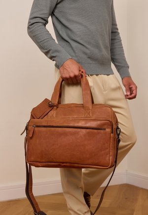 Braune Lederhandtasche mit zwei Obergriffen, einem abnehmbaren Schultergurt, einer vorderen Reißverschlusstasche und einer glatten Textur; rechteckige Form.