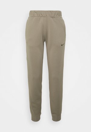 Světlé olivově zelené tepláky s elastickým pasem, zúženými nohavicemi a malým černým logem Nike na levé straně. Hladká textura tkaniny.