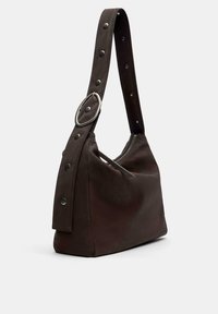 Borsa a spalla in pelle marrone con una tracolla larga, in evidenza accenti in metallo e una texture liscia. Chiusura con zip e dettagli in borchie sulla tracolla.