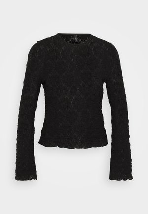 Haut à manches longues noir en dentelle texturée. Il présente un col rond et des bords festonnés. Motif floral complexe sur l'ensemble.