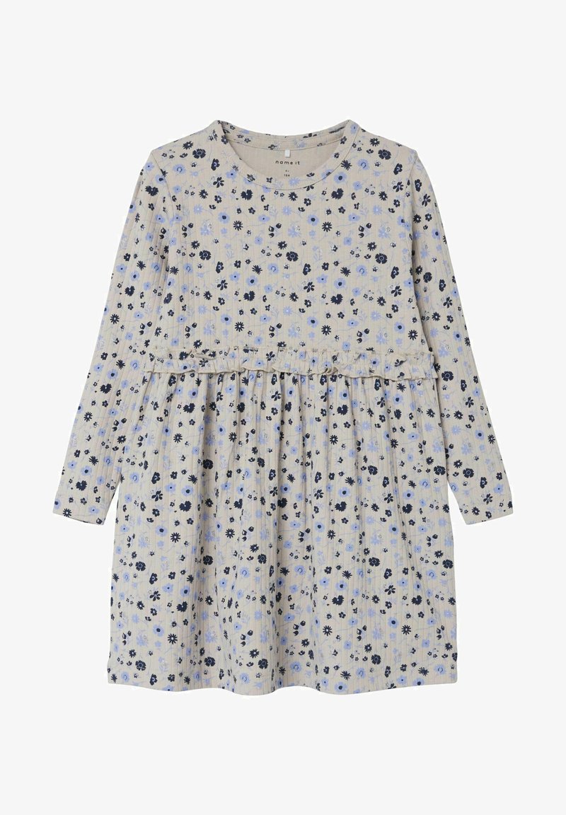 Robe beige à manches longues avec taille froncée, ornée de petits motifs floraux bleus et noirs partout.