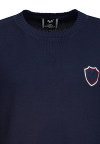 Navy-blauer Strickpullover mit einem strukturierten Ausschnitt und einem Wappenemblem mit roten und grünen Akzenten auf der linken Brust. Größe XL vorhanden.