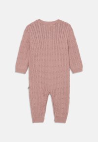 Pleteni romper z dolgimi rokavi v prašnem roza odtenku, ki ima teksturiran vzorec, rebraste manšete in okroglo izrez. Vidnih zaponk ni.