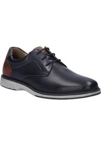 Chaussure en cuir marine avec un design perforé, un talon brun contrastant et une semelle blanche. Style classique à lacets avec un bout arrondi.