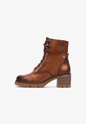 Bruine leren enkelboots met een vetersluiting aan de voorkant, ronde neus en een chunky, textuur-achtige hak. Met gouden oogjes en een zijaccent.