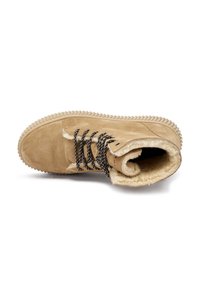 Botas de invierno de ante marrón con suela gruesa y acanalada, cordones en blanco y negro, y suave forro de lana crema en el interior.
