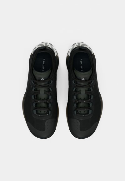 Μαύρα αθλητικά παπούτσια με ομαλή υφή, διαθέτουν περιμετρικό σχέδιο στον γιακά, κορδόνια και διακριτικό σχέδιο στη μέση της σόλας για επιπλέον αντίθεση.