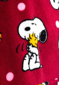 Fleece blanket featuring a red background with white and pink dots, displaying Snoopy with Woodstock in black and yellow outlines.