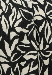 Tela en blanco y negro con un patrón abstracto de hojas y costuras visibles en material texturizado.