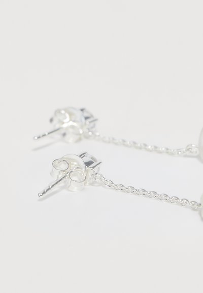 Sidabrinės auskarai, papuošti pakabuko vienaragio dizainais ir grandinėle. Glotnus paviršius su poliruotu apdaila ir akį traukiančiais detalėmis.