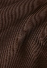 Dark brown fabric with a ribbed texture, showing alternating raised and recessed lines, creating a wavy pattern throughout.