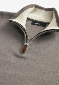 Grijze gebreide pullover met kwartrits en een crèmekleurige kraag, voorzien van een metalen rits en een bruin leren trekband. Het label geeft "NEXT" aan.